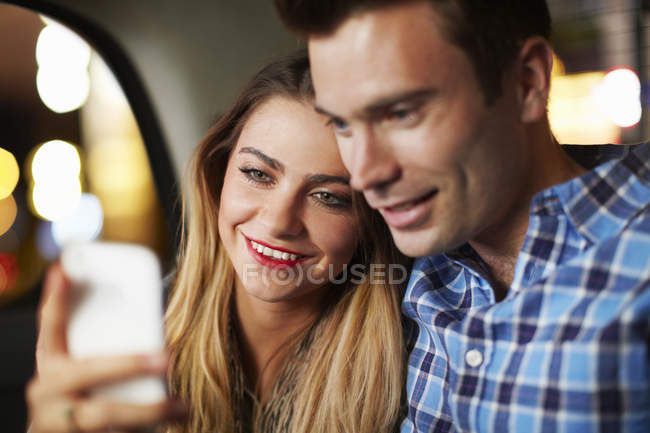 Couple looking at smartphone city taxi at night — Stock Photo