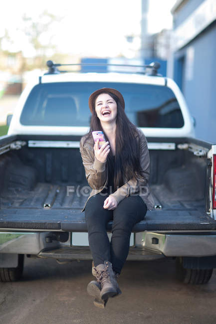 Retrato de una joven mujer sentada en la parte trasera del camión - foto de stock