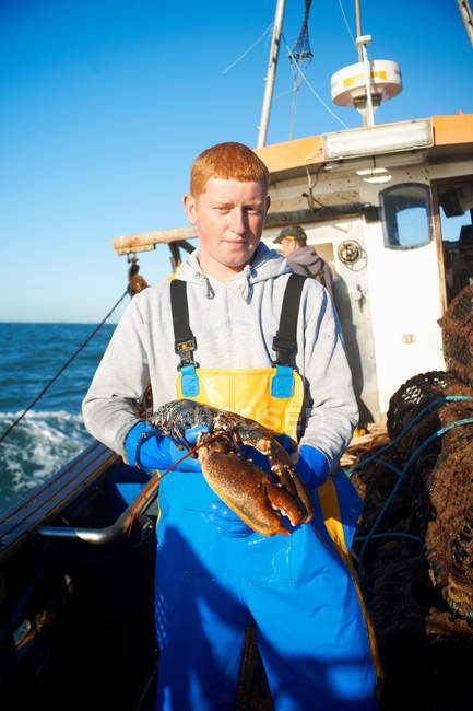 Fisherman holding lobster on boat — Stock Photo