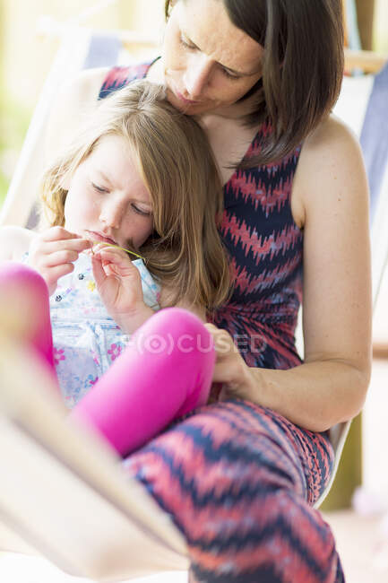 Hija sentada en el regazo de la madre - foto de stock