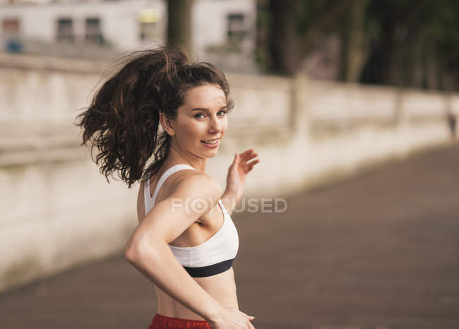 Femmina corridore guardando sopra la spalla durante la corsa — Foto stock