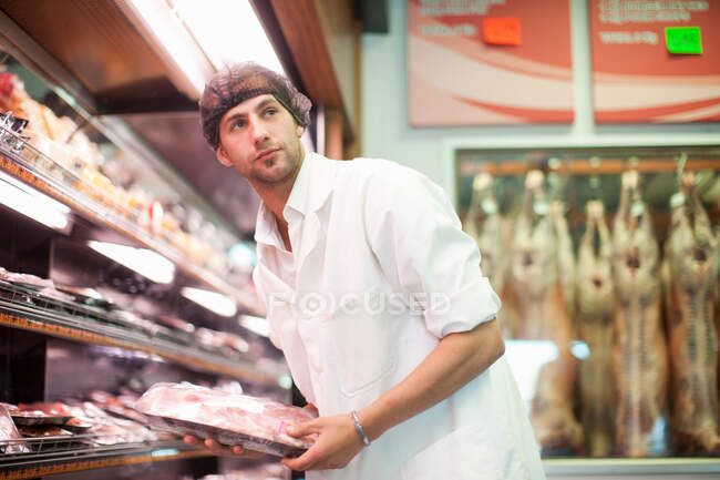 Carnicero sosteniendo paquete de carne en la carnicería - foto de stock