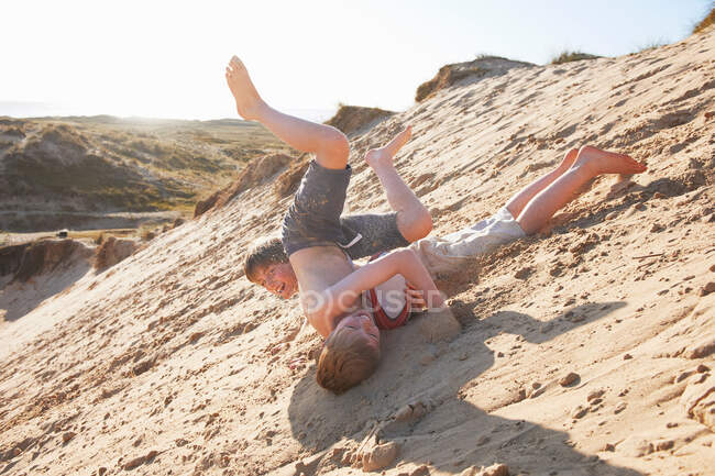 Two boys rolling on beach — Stock Photo