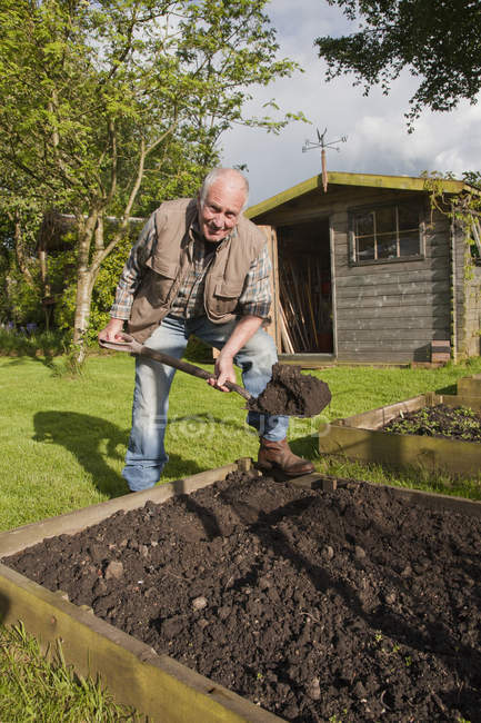 Senior man, digging soil in garden — Stock Photo