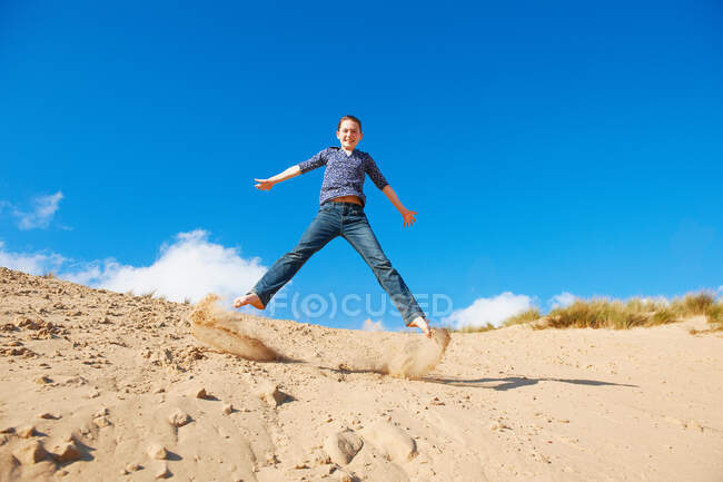 Дівчина-підліток стрибає на піску — стокове фото