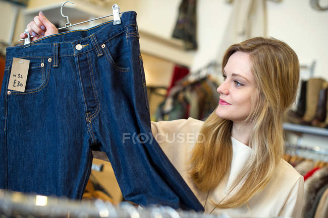 Jeune femme regardant une paire de jeans — Photo de stock