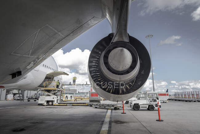 Rear view of A380 jet engine with ground crew loading freight — Stock Photo