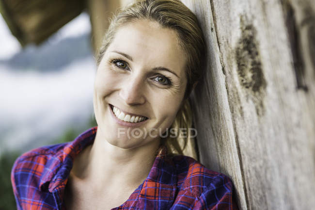Mulher encostada à parede exterior da cabana de madeira — Fotografia de Stock