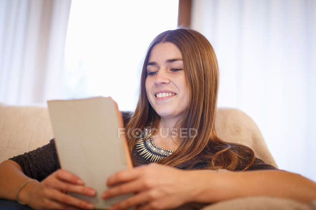 Jovem mulher usando tablet digital no sofá — Fotografia de Stock
