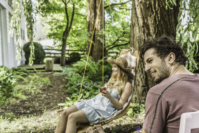 Jeune couple assis dans le jardin et regardant loin — Photo de stock