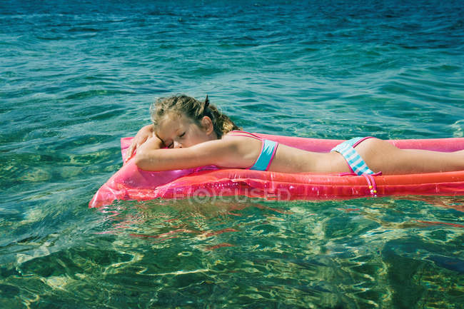 Chica joven en colchón inflable en agua de mar - foto de stock