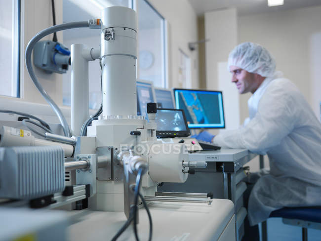 Чоловічий вчений в захисному одязі з використанням електронного мікроскоп в лабораторії — стокове фото