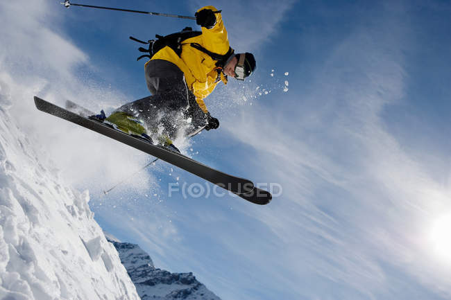Esquiador macho saltando sobre cume da montanha — Fotografia de Stock