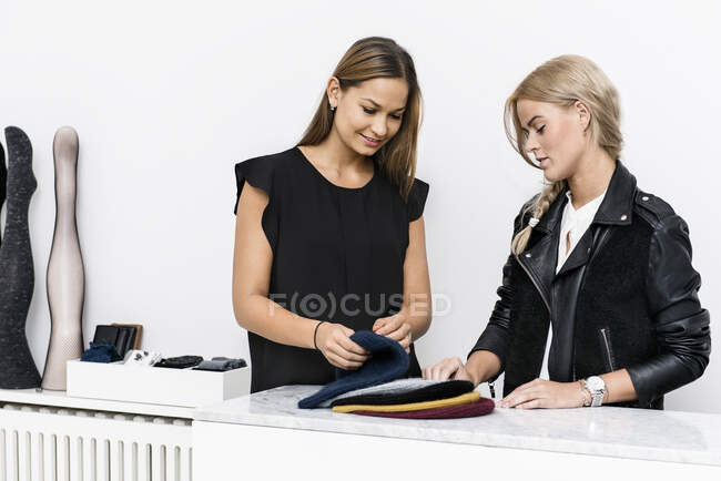 Female colleagues examining beanie hats — Stock Photo