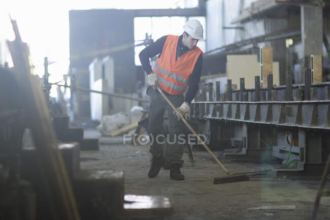 Factory worker sweeping up in concrete reinforcement factory — Stock Photo