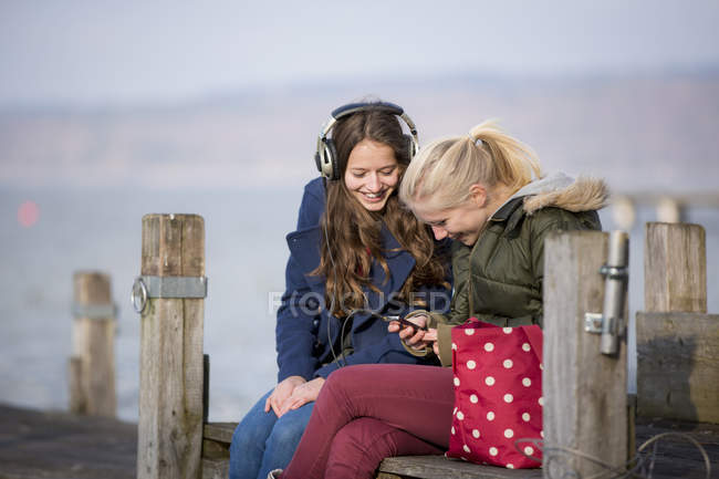 Дівчата-підлітки сидять на джинсах і слухають музику — стокове фото