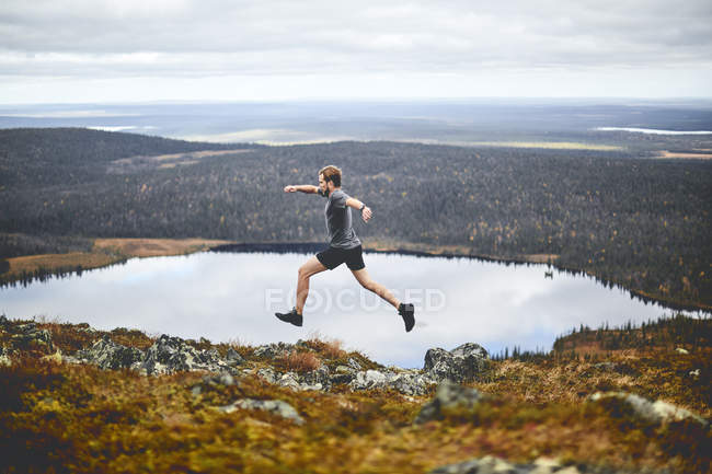 Man sprinting on rocky cliff top, Keimiotunturi, Lapland, Finland — Stock Photo