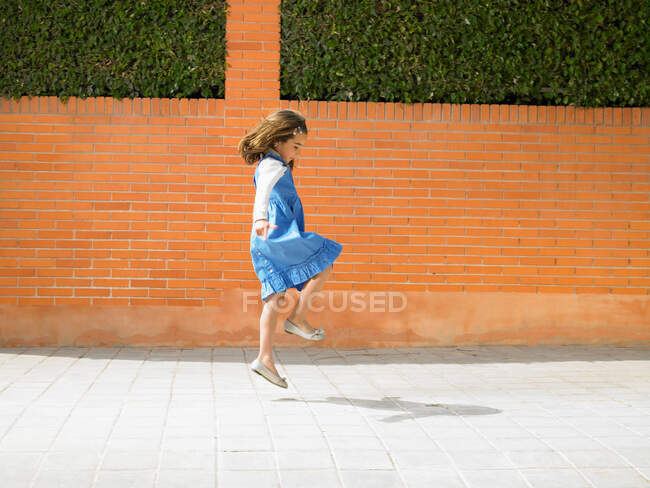 Маленькая девочка прыгает по тротуару — стоковое фото