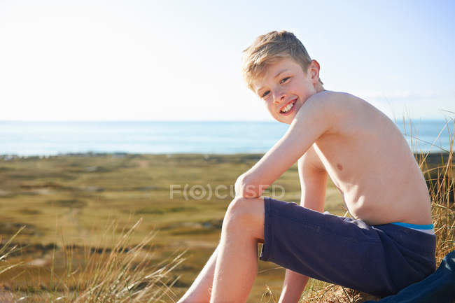 Garçon assis sur la plage — Photo de stock