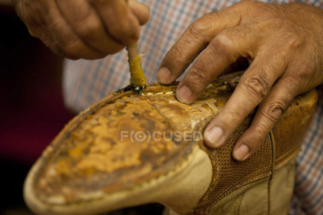 Cobbler aplicando pegamento en la suela de la bota - foto de stock