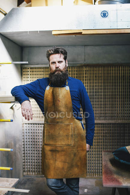 Porträt eines erwachsenen Handwerkers, der sich an ein Regal in der Orgelwerkstatt lehnt — Stockfoto