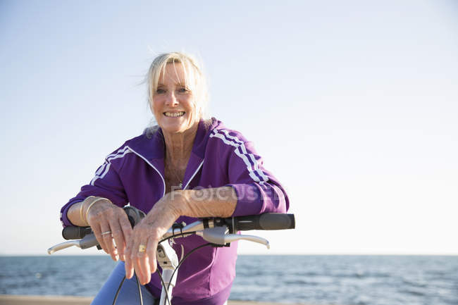 Senior woman on bicycle by beach — Stock Photo