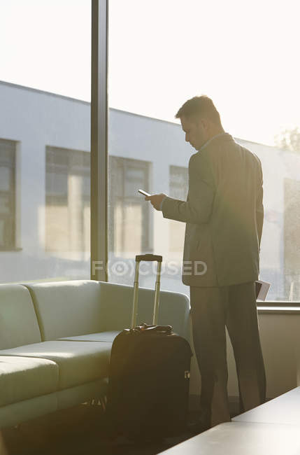 Зрілий чоловік в аеропорту за допомогою мобільного телефону — стокове фото