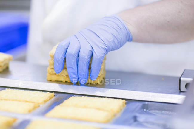 Imagem cortada do trabalhador da fábrica em luvas de látex segurando tofu — Fotografia de Stock