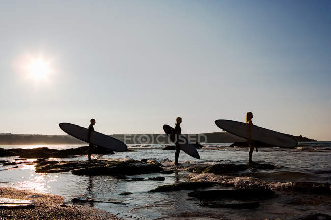 Three people holding surfboards standing — Stock Photo