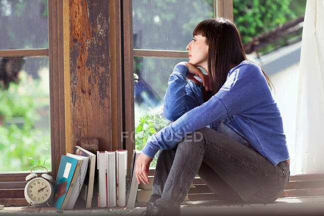 Woman sitting on windowsill — Stock Photo