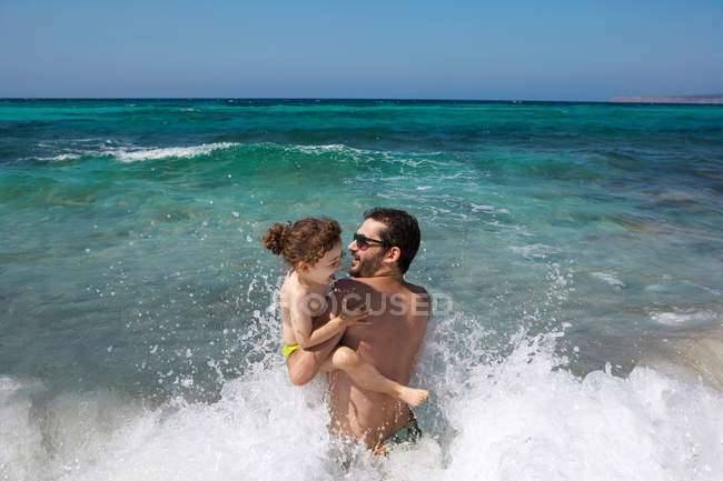 Батько і дочка грають у хвилях — стокове фото