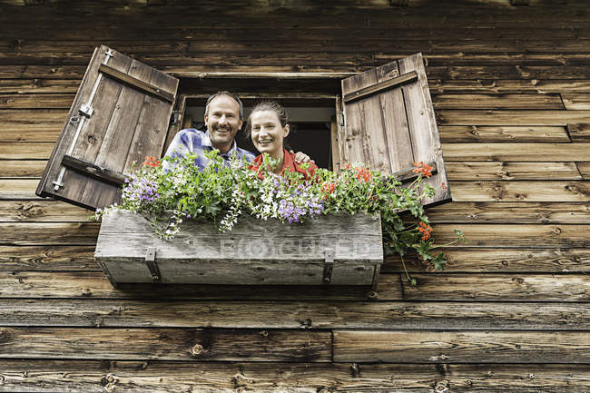 Portrait de couple à la fenêtre du chalet — Photo de stock
