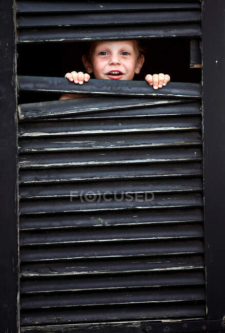 Tout-petit garçon regardant par la fenêtre — Photo de stock