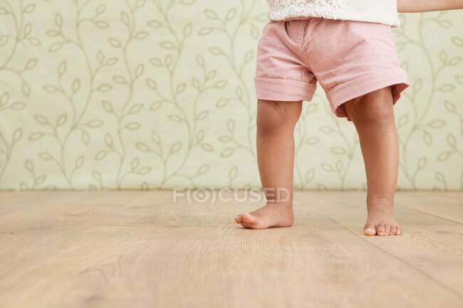 Baby girl taking first steps, low section — Stock Photo