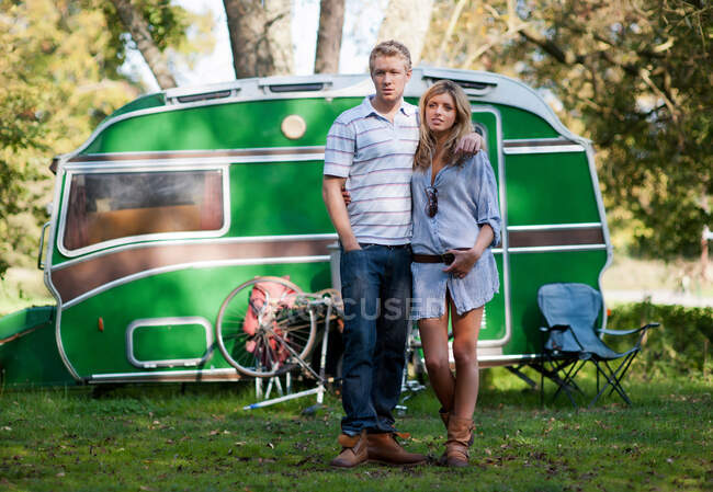 Couple standing outside trailer in park — Stock Photo