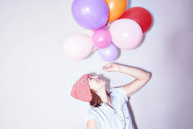 Studio shot of young woman holding up bunch of balloons — Stock Photo