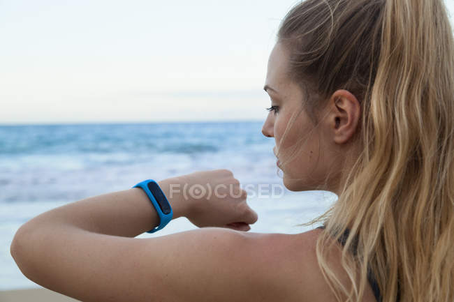Close up of young female runner checking smartwatch time on beach, Dominican Republic, The Caribbean — Stock Photo
