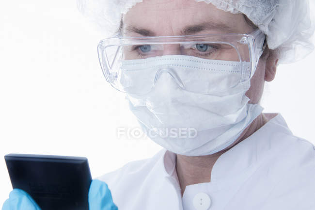 Médico en mascarilla usando tableta - foto de stock