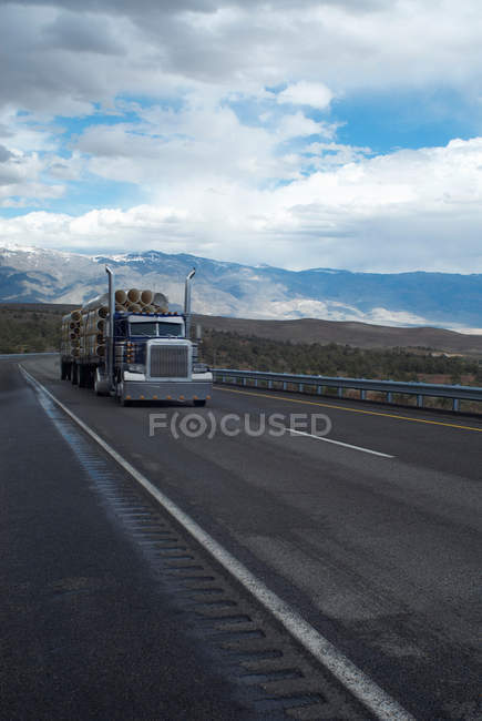 Camión que lleva troncos en paisaje rural - foto de stock