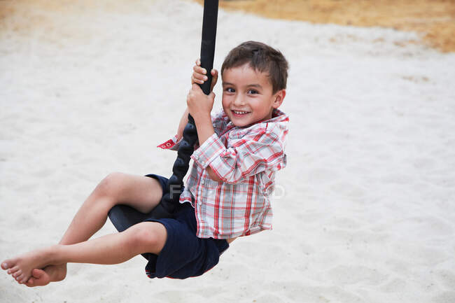 Мальчик играет на качелях на детской площадке — стоковое фото