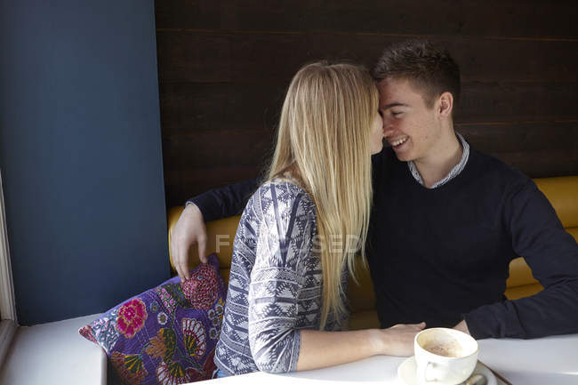 Romántica pareja joven cara a cara en la cafetería - foto de stock