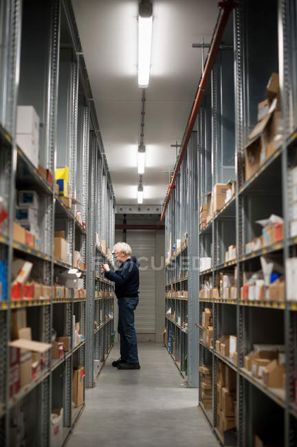 Trabajador de almacén masculino seleccionando artículos de estanterías - foto de stock