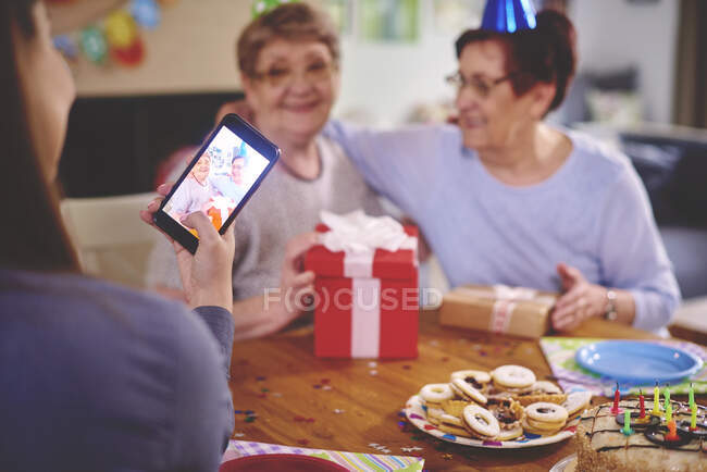 Daughter taking photo of mother and friend at birthday party — Stock Photo