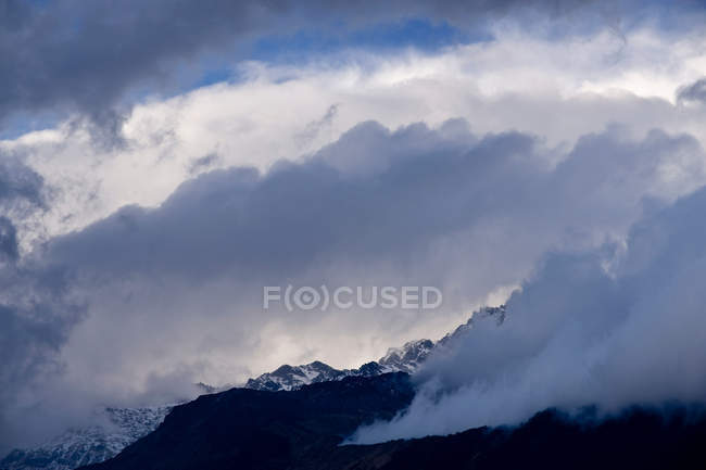 Nuvole sopra la montagna innevata — Foto stock