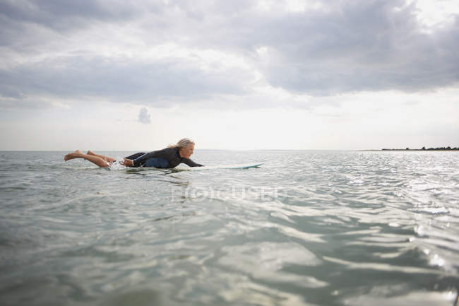 Старша жінка на дошці для серфінгу в морі — стокове фото