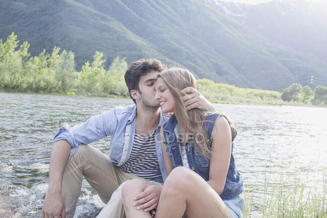 Giovane baciare fidanzata sulla riva del fiume Toce, Piemonte, Italia — Foto stock