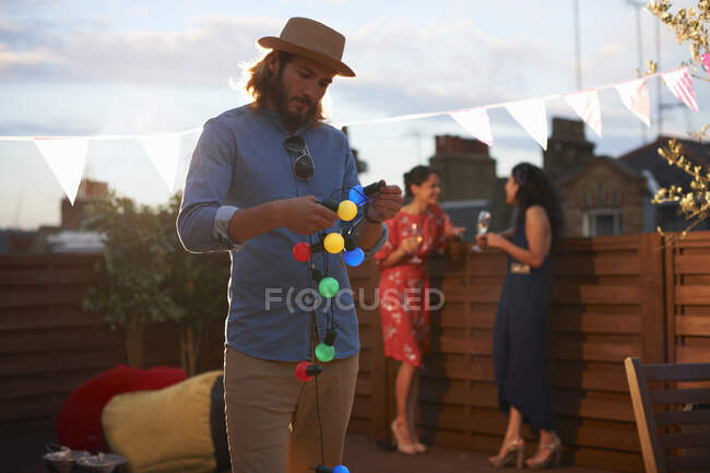 Mann hängt Gartenlichter für Party am frühen Abend auf — Stockfoto
