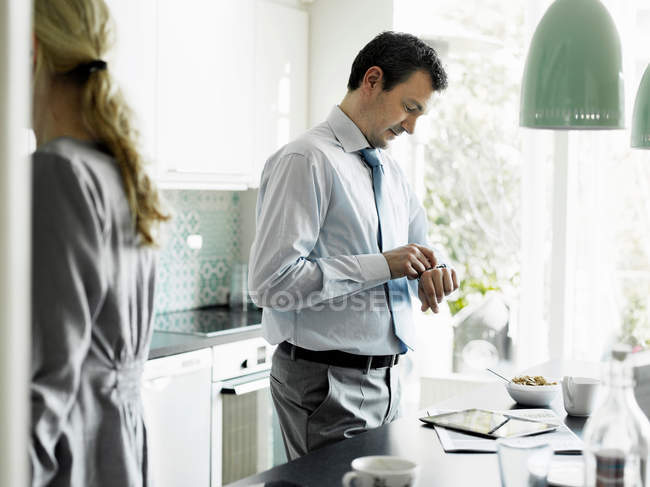 Mature businessman checking time in kitchen — Stock Photo