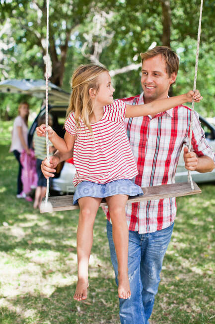 Padre empujando hija en swing - foto de stock