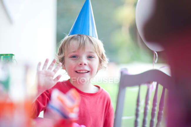 Young boy waving at birthday party — Stock Photo
